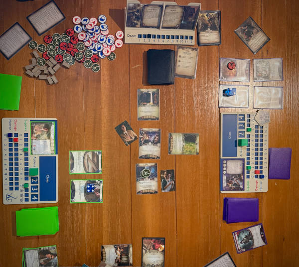 photo taken from over the table showing Arkham Horror the Card Game with 3D-printed upgrades and card sleeves